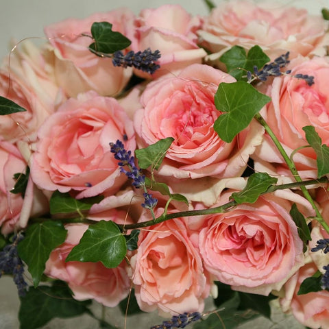Bouquet of peachy-pink roses with green leaves and blue lavender sprigs