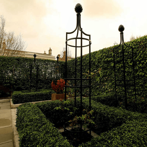 Two black metal obelisk trellises with rounded finials and lattice side panels