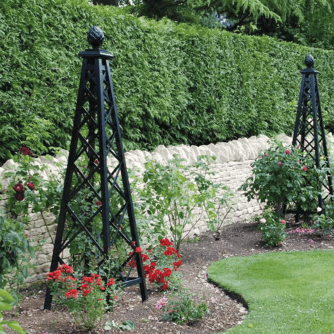 Pair of black metal pyramid garden obelisks in a landscaped rose garden